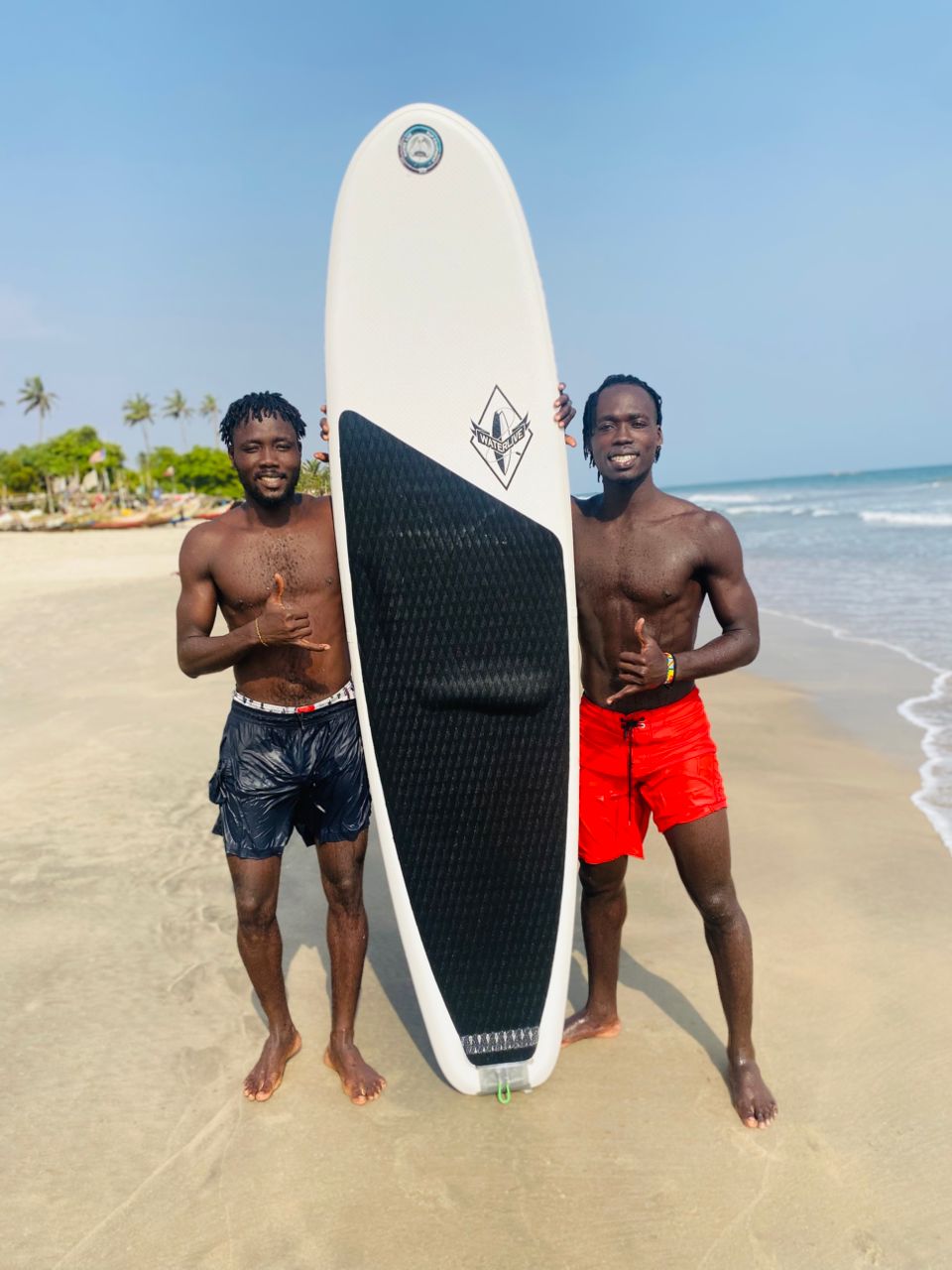 Solomon and Daniel holding a surfboard on Kokrobite beach